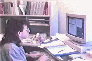 Retro photograph of Todd sitting in front of a computer with a mullet hairstyle.